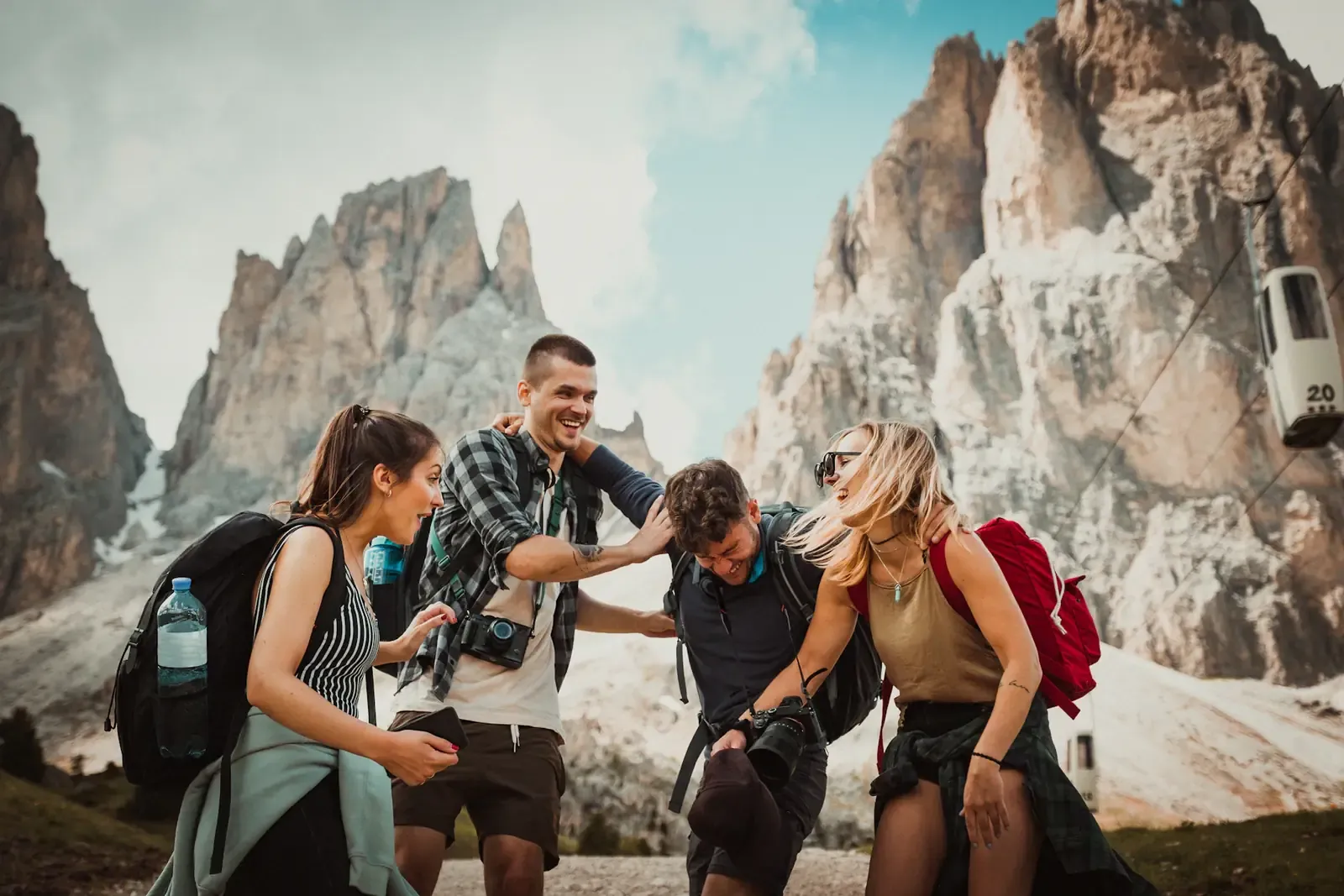 Cuatro amigos con mochilas riéndose durante una caminata entre montañas rocosas