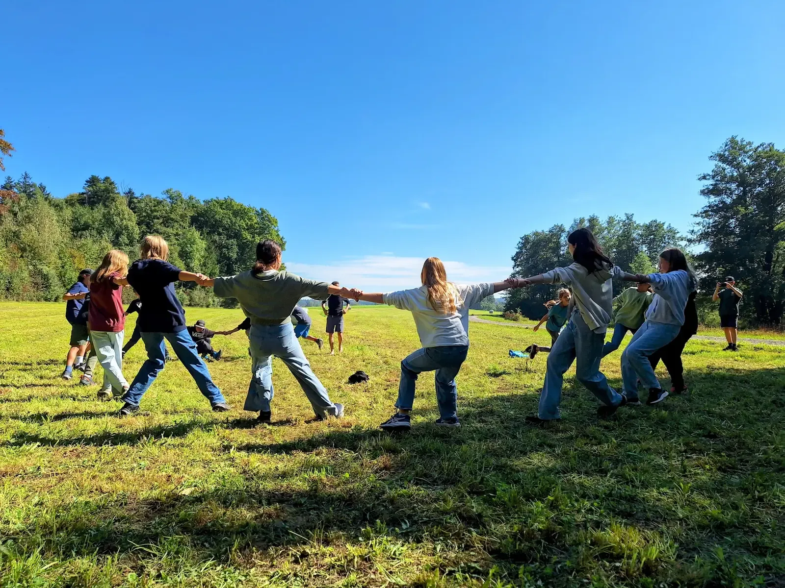 Grupo jalando juntos en un juego de equipo sobre un campo de zacate, en un día soleado