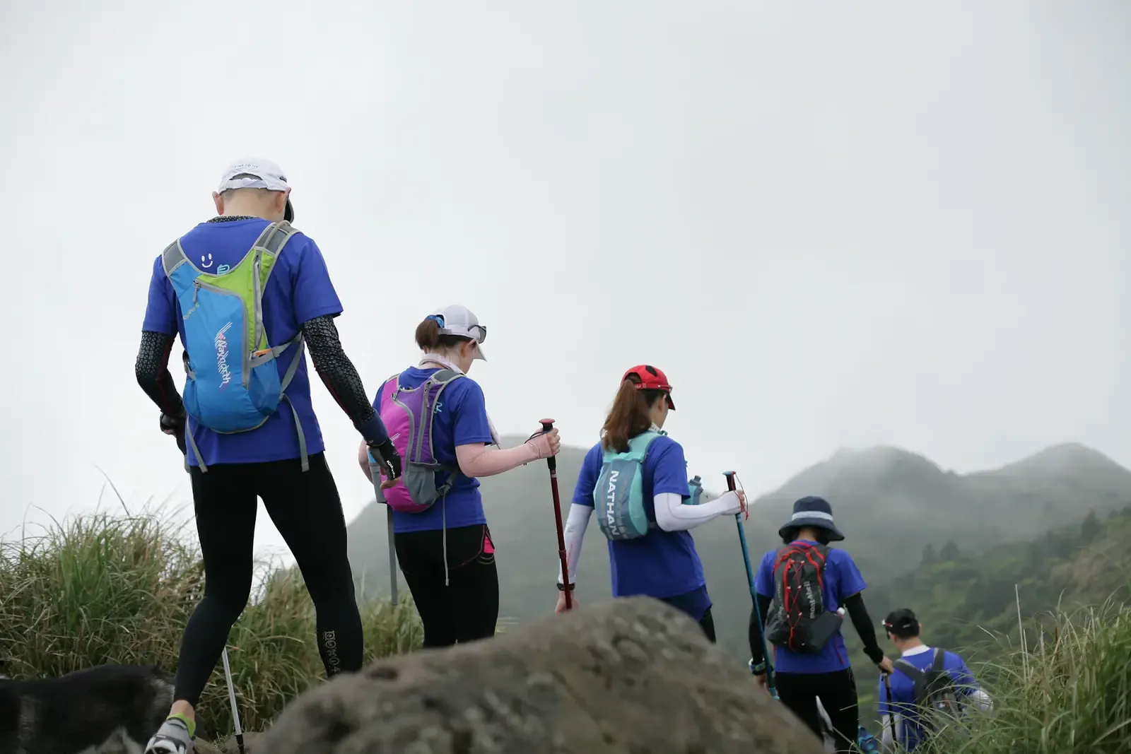 Equipo con camisetas iguales subiendo un cerro entre la niebla